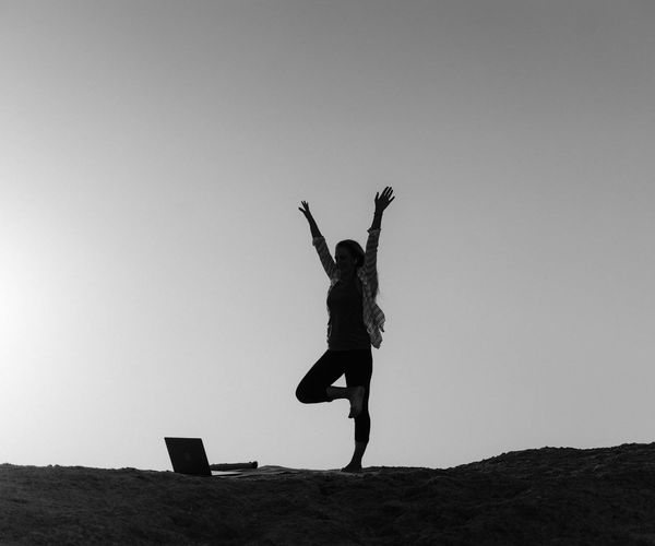 Silhouette of a person stretching during sunrise, feeling energized.